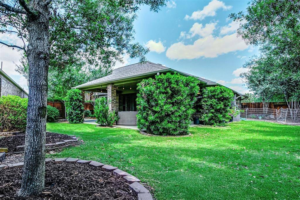The backyard features five mature live oak trees that offer shade. A covered patio provides a comfortable space for outdoor relaxation and entertaining. The yard is enclosed by a wooden fence and backs to a peaceful greenspace, with no rear neighbors for added seclusion.