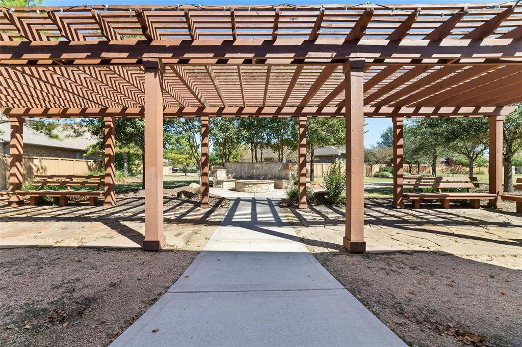 The pergola area is ideal for social gatherings, featuring built-in bench seating and a cozy outdoor firepit.