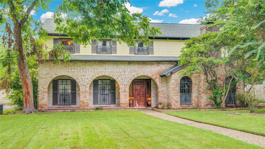 Charming two-story home with distinctive brick arches, a solid wood front door, and a beautifully manicured front lawn—now featuring unobstructed windows for a clean, updated look.