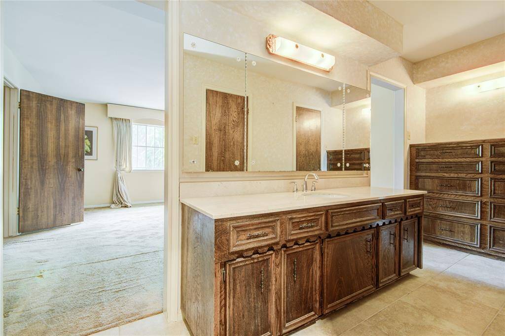 The ensuite bathroom features a long vanity with dual-opening mirrored cabinets and built-in drawers for added storage and convenience.