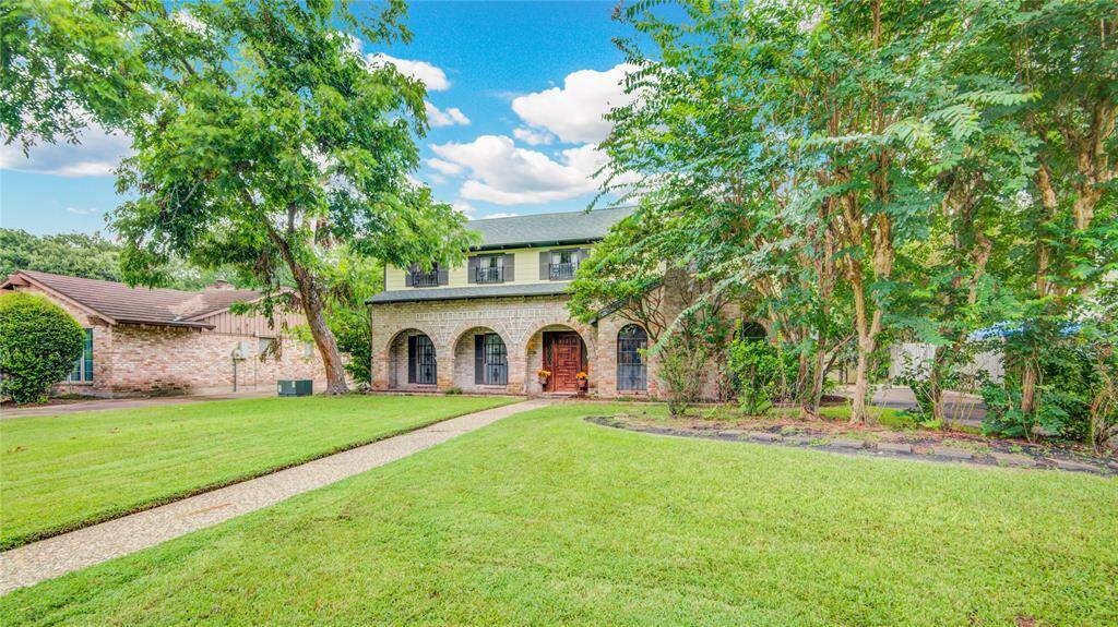 A side perspective reveals the lush front landscaping and charming brick façade, highlighting the home’s curb appeal from every angle.