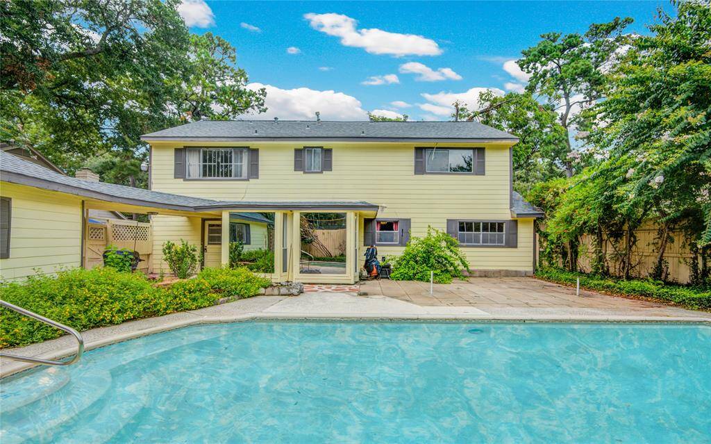 A sparkling pool takes center stage, with the beautifully landscaped yard, the home just beyond, and the garage to the left creating a picture-perfect backyard retreat.