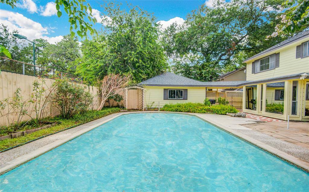 From the pool’s end, enjoy a view of the tennis courts to the left, the home to the right, and the garage with a charming window straight ahead, all framed by lush landscaping.