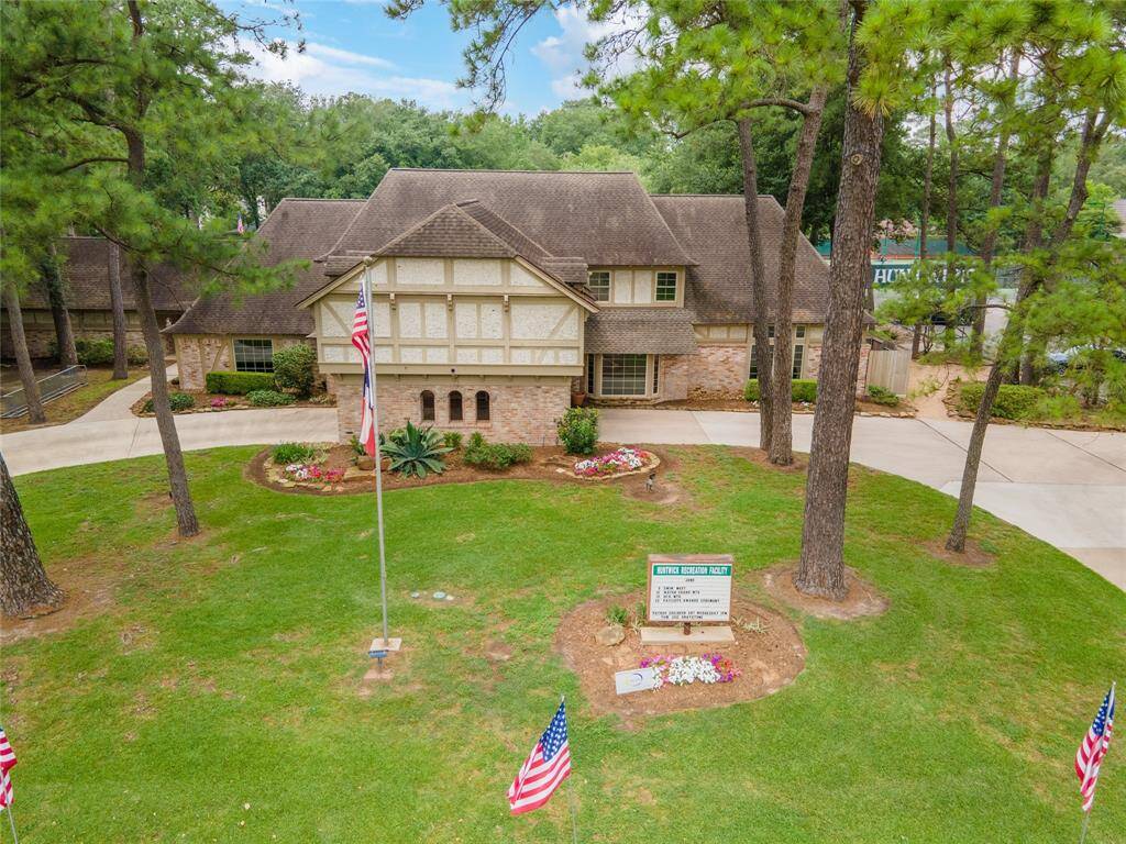 An aerial view showcases the subdivision’s elegant clubhouse with a grand circle drive, stately porte-cochère, and ample parking, all set within a beautifully landscaped community setting.