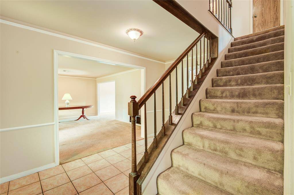The front foyer welcomes you with a classic staircase and leads into a spacious formal living room, ideal for a large dining area or home office.