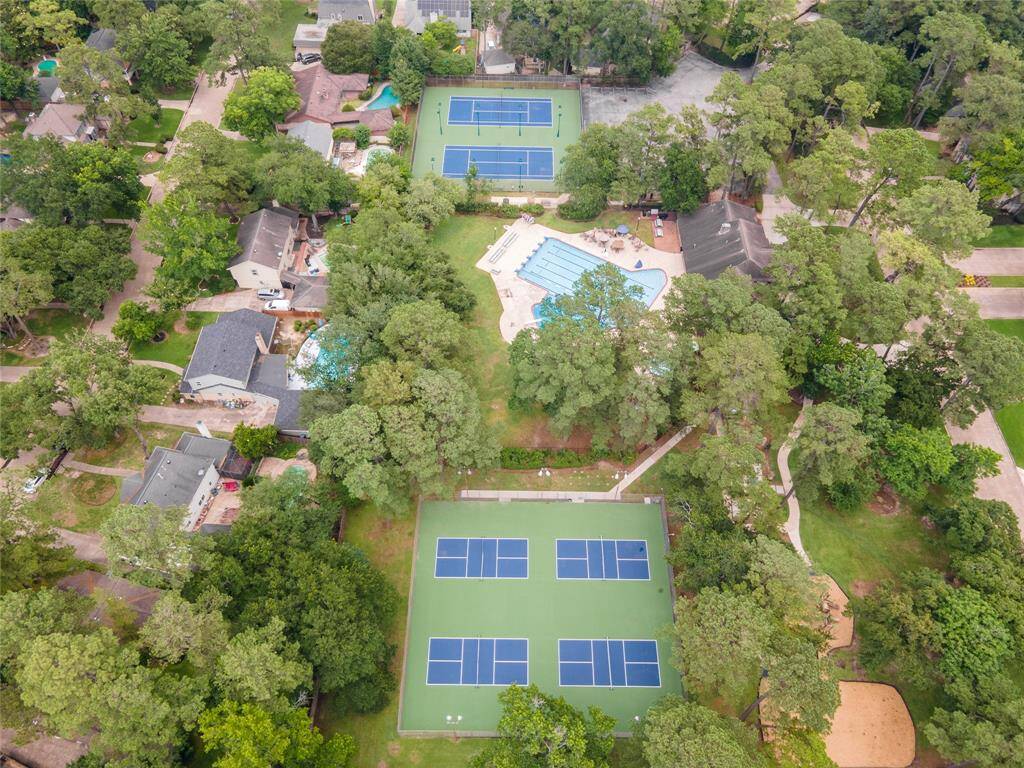 This aerial view captures the vibrant community amenities, with the pickleball courts in the foreground, the sparkling pool at the center, and the tennis courts just beyond—offering a full view of active lifestyle options.