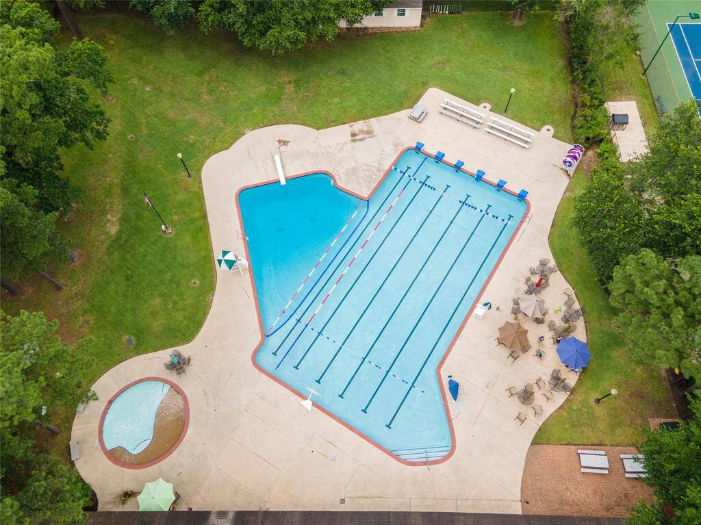 A close-up aerial view of the pool reveals designated swim lanes, a spacious swimming area with a diving board, a separate children's section, and plenty of seating and benches surrounding the deck for relaxation and gathering.