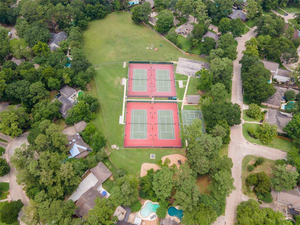 An aerial view highlights a separate set of tennis courts within the subdivision, nestled amid mature trees and greenery, offering additional space for recreation in a serene setting.