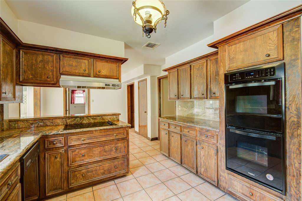 next is the The kitchen features a built-in double oven and gas cooktop, with a clear view into the light-filled breakfast area beyond.