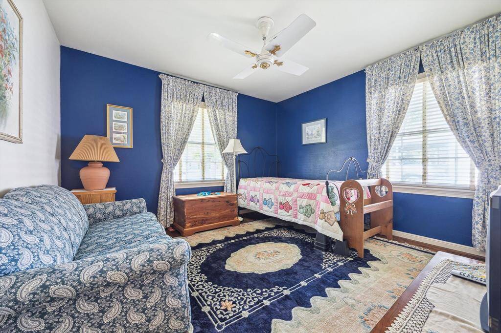 [PRIMARY BEDROOM]  The main bedroom makes a bold yet calming statement with its rich blue walls, creating a cozy, cocoon-like retreat filled with personality and style. Warm hardwood floors balance the deep tones beautifully, while large windows bring in soft natural light that enhances the serene atmosphere.