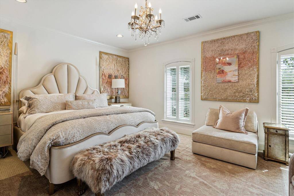 This charming secondary bedroom offers dual windows with views of the front lawn, framed by custom wood shutters that add a touch of elegance. Built-in shelving and a desk with knee space make this room perfect for work or study, while custom crown molding and recessed LED lighting create a warm, inviting atmosphere. The room also features neutral carpet flooring and access to a well-appointed reach-in closet with drawers, long hanging space, and open shelving for optimal organization.