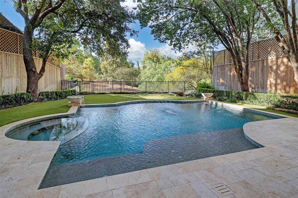 This resort-style backyard features a heated pool and spa with elegant fountain features, creating a tranquil oasis for relaxation and entertainment. The lush, year-round artificial turfed lawn and beautiful landscaping provide a stunning backdrop, while a covered patio offers the perfect space for outdoor dining and gatherings. Exterior cameras throughout the property ensure both security and peace of mind, blending luxury with practicality.