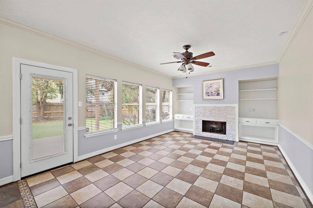 Refined living space with oversized windows offering serene backyard views, custom built-ins,  and stone fireplace.