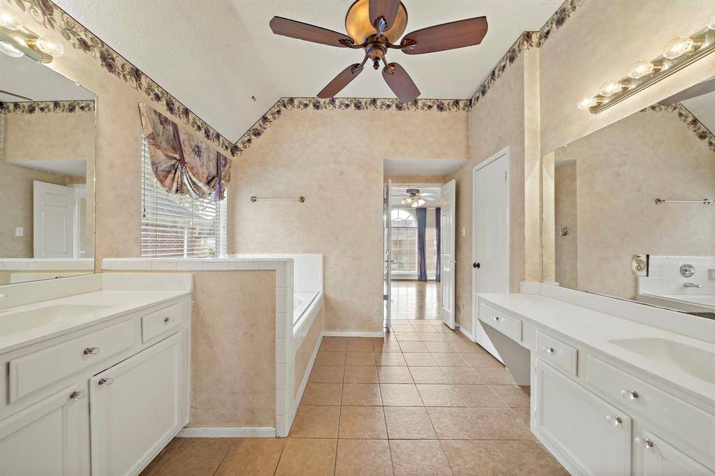 The spacious primary bathroom offers a soaking tub, separate tiled shower, and dual vanities.