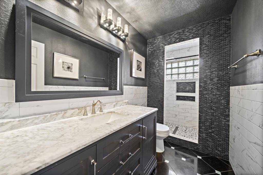 The recently updated 2nd bath showcases a marble countertop, rich black tile accents, and walk-in shower for a sleek and modern design.