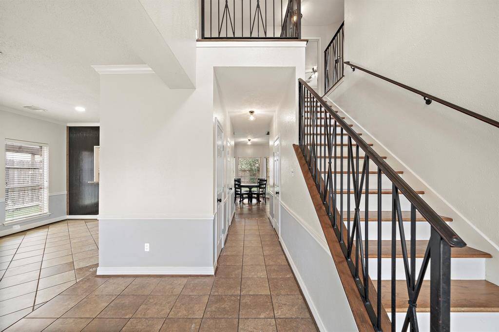 The inviting entryway showcases elegant wrought iron railings, neutral tones, and an open flow leading to spacious living and dining areas. Perfect for welcoming guests with style and warmth!