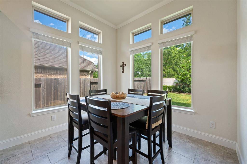 Bright dining area with large windows offering a view of the backyard. Features neutral tile flooring, and ample natural light, creating an inviting space.