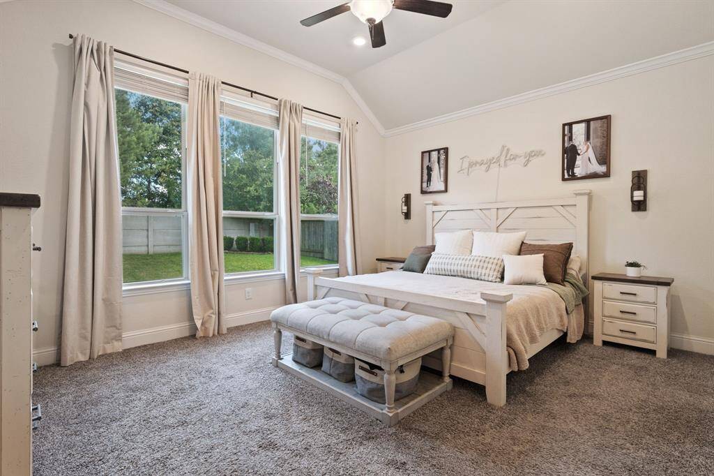 This welcoming primary bedroom features large windows offering a serene view of the backyard. The room is bright and airy with neutral tones and elegant decor.