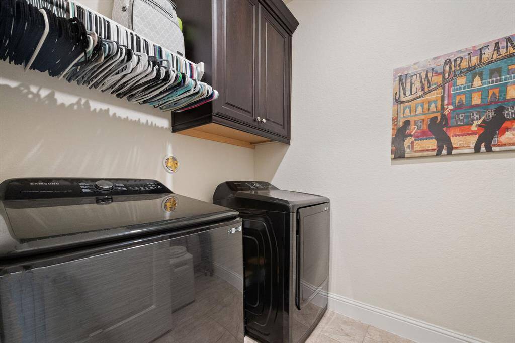 This laundry room features ample cabinet storage, a convenient hanging rod.