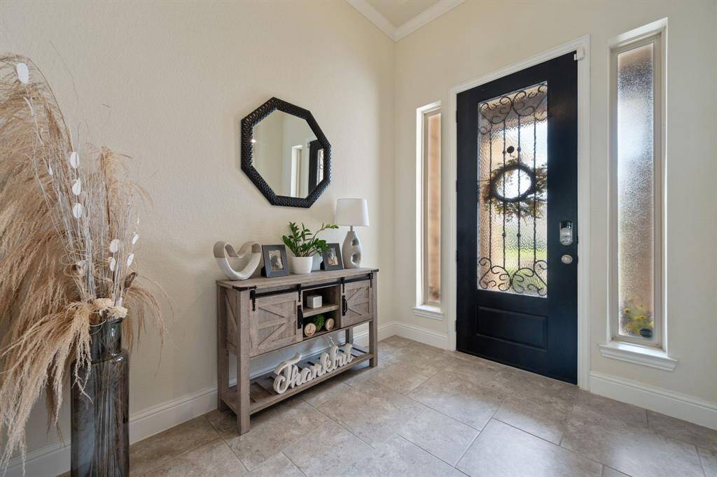 This inviting entryway features a stylish black door with decorative glass panels, flanked by narrow windows for natural light.