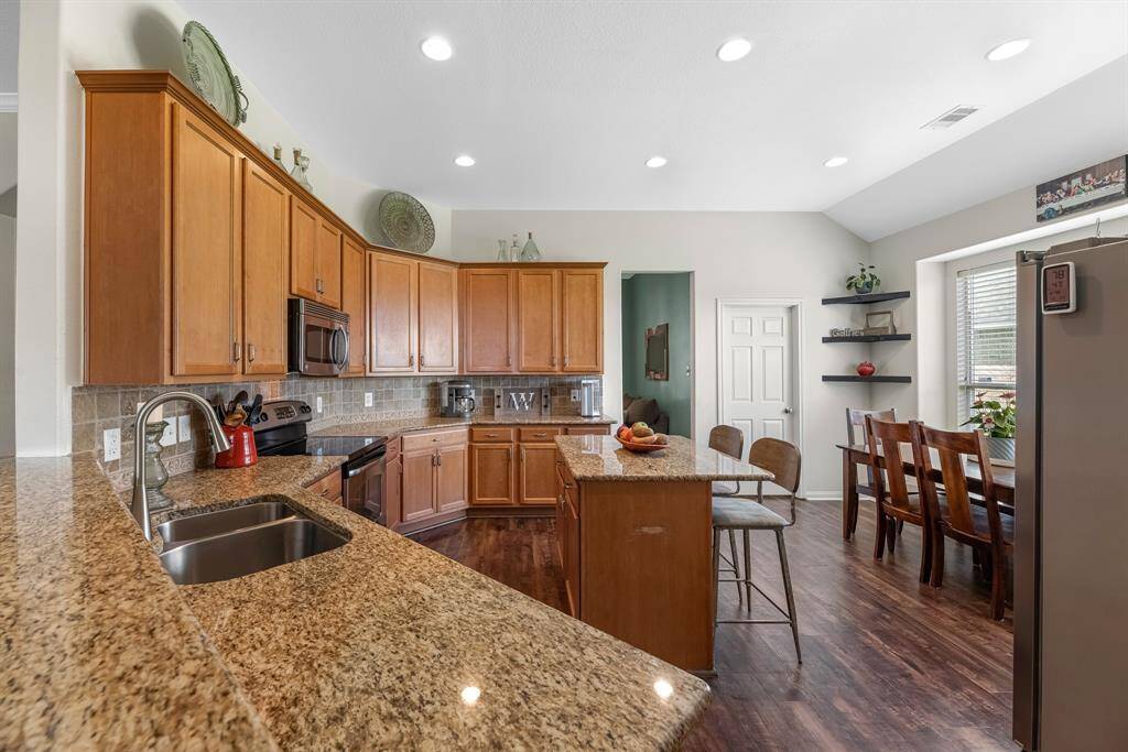 Bright, open kitchen with high-top breakfast bar, granite counters, 42" cabinets, island, large pantry, and space for breakfast table.