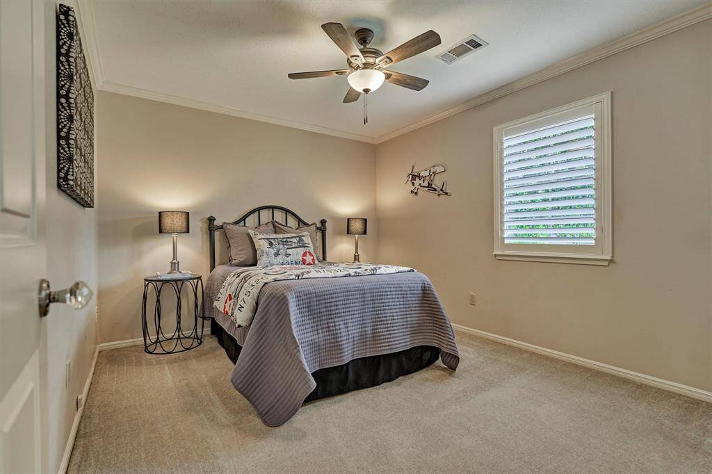 This bedroom room is well-lit with natural light from a window with plantation shutters, creating a comfortable and inviting space.