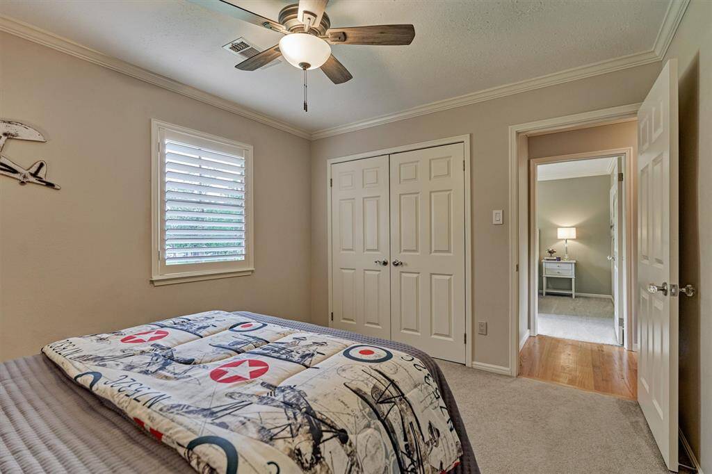 Ceiling fan, plush carpet and ample closet space finish out the room. The bedroom opens into a hallway with hardwood flooring.