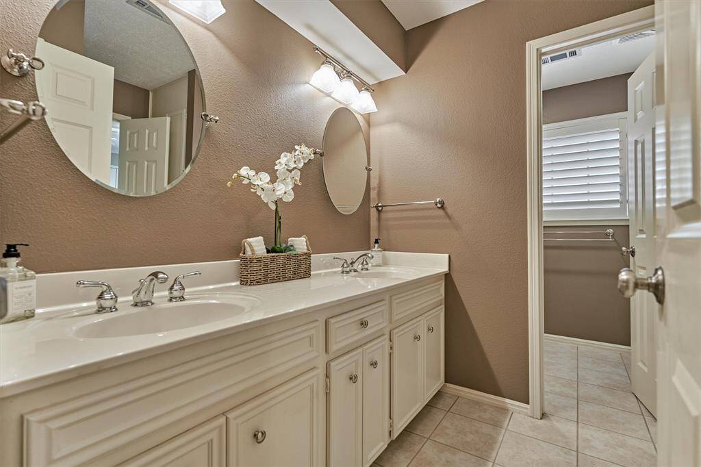 Spacious secondary bathroom with dual sinks and ample storage, including a dedicated linen area in the shower room.