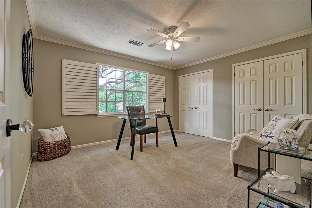 4th bedroom room is styled as an inspiring home office. It features a large shuttered window with a spectacular view of the patio's sprawling live oak tree.  A Ceiling fan & dual closets provide ample storage, making it ideal for productivity and organization.
