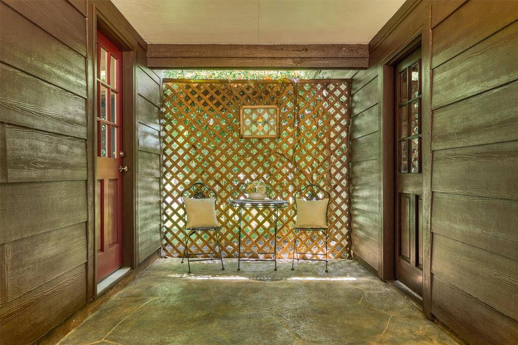 Charming sitting area in the covered breezeway, enhanced by a lattice adorned with flowering vines.