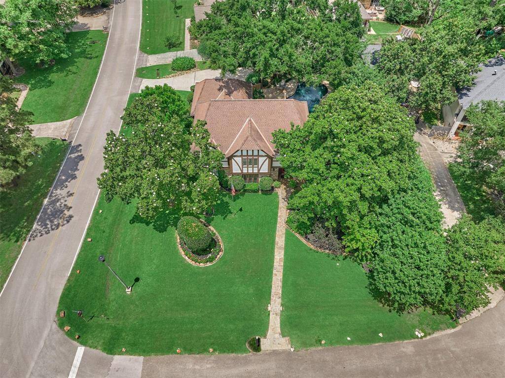 Charming Tudor-style home on a corner lot with lush landscaping and mature trees. The property features a well-maintained lawn and a welcoming flagstone walkway leading to the entrance. Ideal for those seeking a picturesque and serene neighborhood setting.