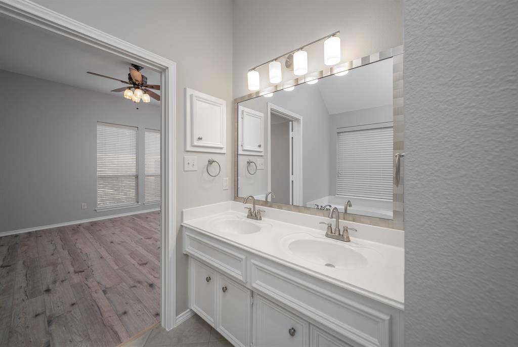 Enjoy a dual sink vanity that rests under a gorgeous framed mirror and elegant lighting.
