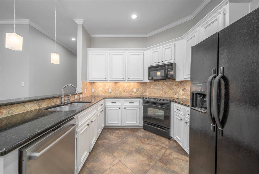 Beautiful drop lights illuminate the breakfast bar in this ideal kitchen. Note the recessed lighting and under-cabinet lighting that accent the beautiful countertops and backsplash.
