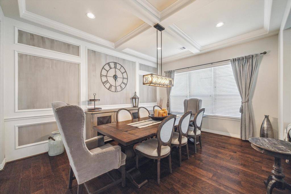 This formal dining room features elegant coffered ceilings, hardwood floors, and a large window with natural light. Family gatherings and holiday meals just become that much more special.