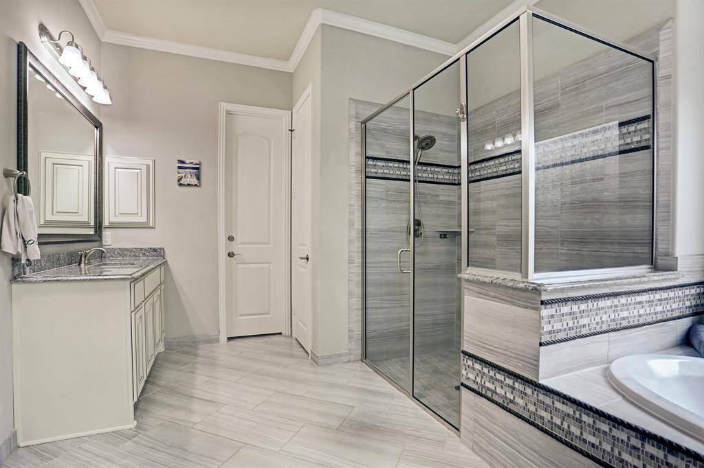 Another view of the primary bathroom. The neutral color palette and tile accents create a sleek, contemporary look.