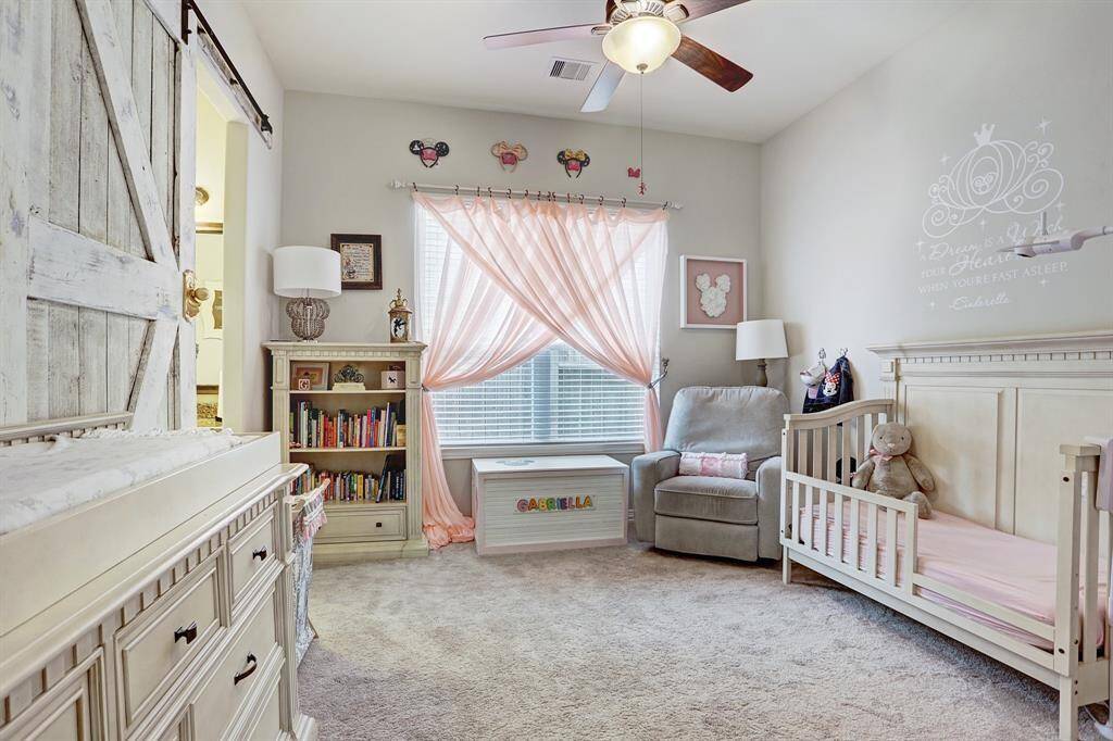 Secondary bedroom currently being used for a nursery has a sliding barn door and heigh ceilings.