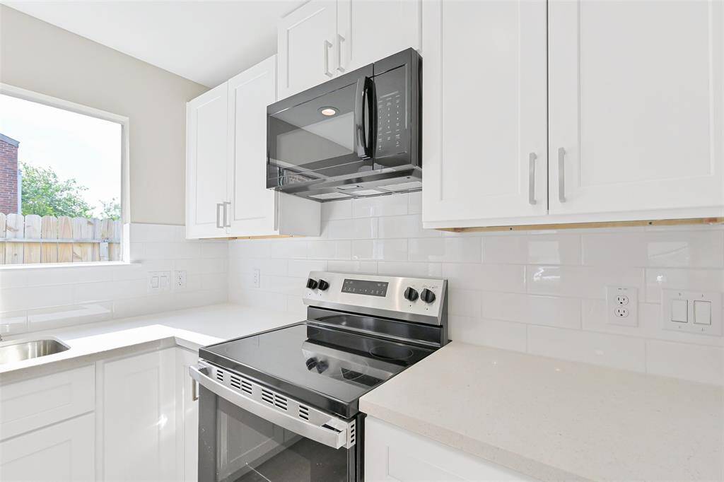 The chef's kitchen is equipped with brand-new stainless steel appliances, a sleek microwave, and plenty of shaker cabinetry, making meal prep a breeze.