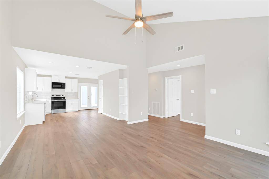 An alternate view reveals the sleek, newly updated kitchen boasting new stainless steel appliances, quartz countertops, and a chic white subway tile backsplash.