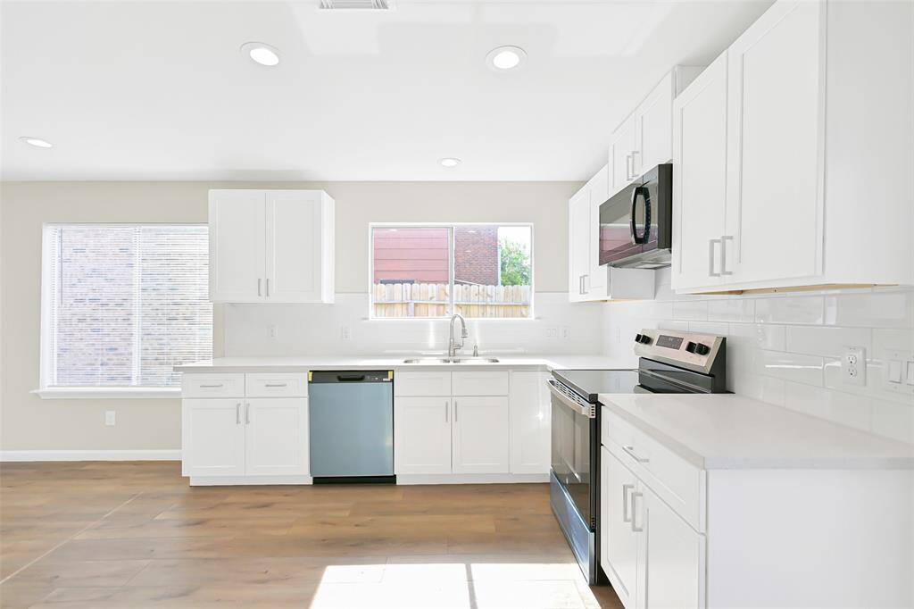 The spacious kitchen boasts white shaker cabinetry, quartz countertops, and beautiful subway tile backsplash, along with large windows that flood the space with natural light.