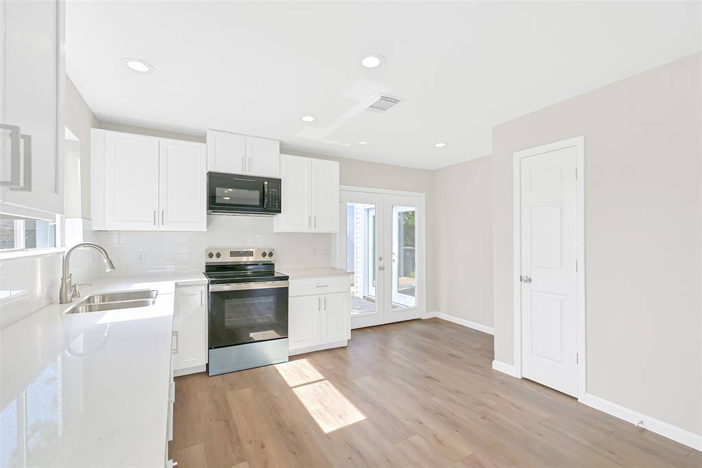 Bright recessed lighting illuminates the kitchen, highlighting the clean lines of the cabinetry and providing a functional workspace. A spacious pantry offers convenient storage for all your kitchen essentials.