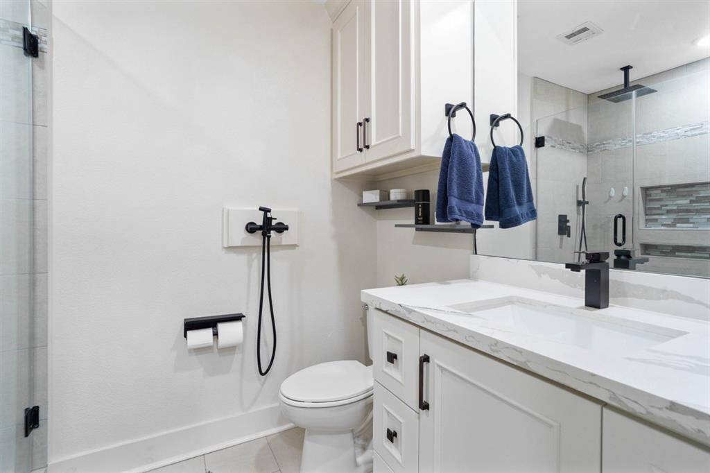 Secondary bathroom also features separate glass shower, quartz countertops and elongated power flush toile + handheld bidet