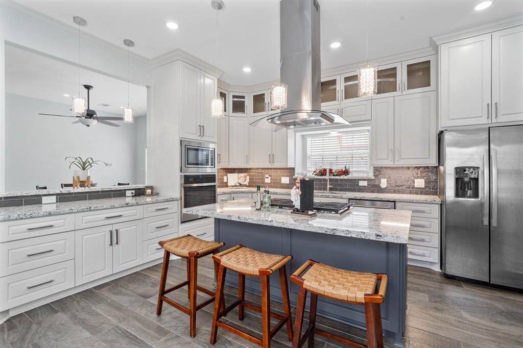 This remodeled kitchen offers SS appliances, quartz countertops, 5-burner gas cooktop, 42" custom wood cabinetry with soft-close feature & under cabinet lighting.
