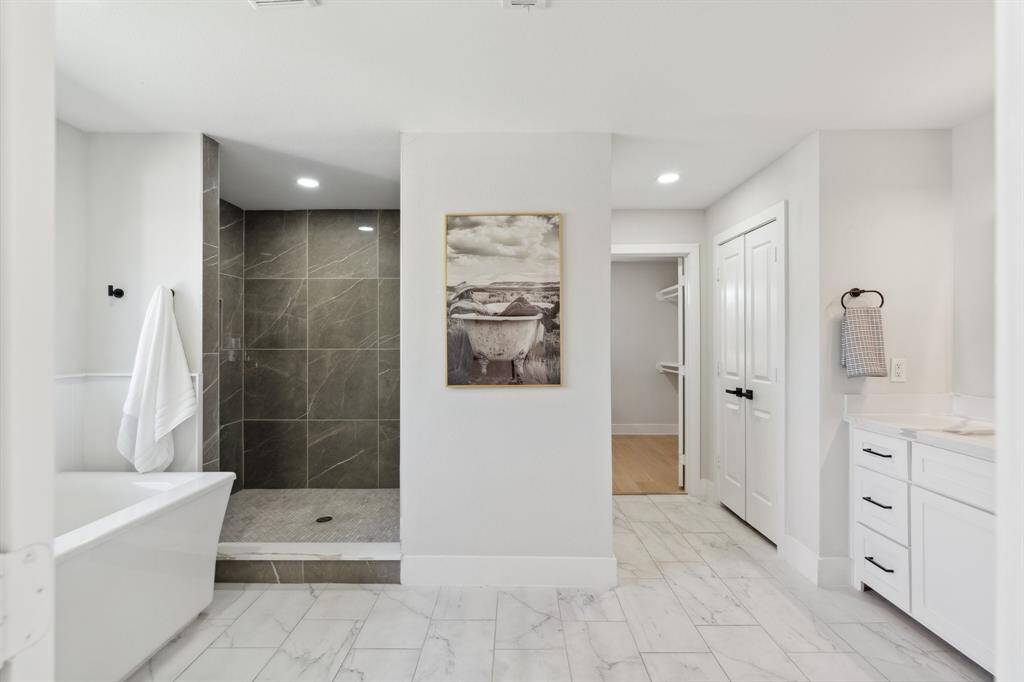The spa-like primary bathroom, featuring a luxurious soaking tub, seperate shower, double vanities, and a spacious walk-in closet.
