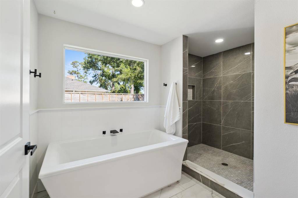 The soaking tub, framed by a sun-filled window, creates a spa-like moment of calm and comfort.