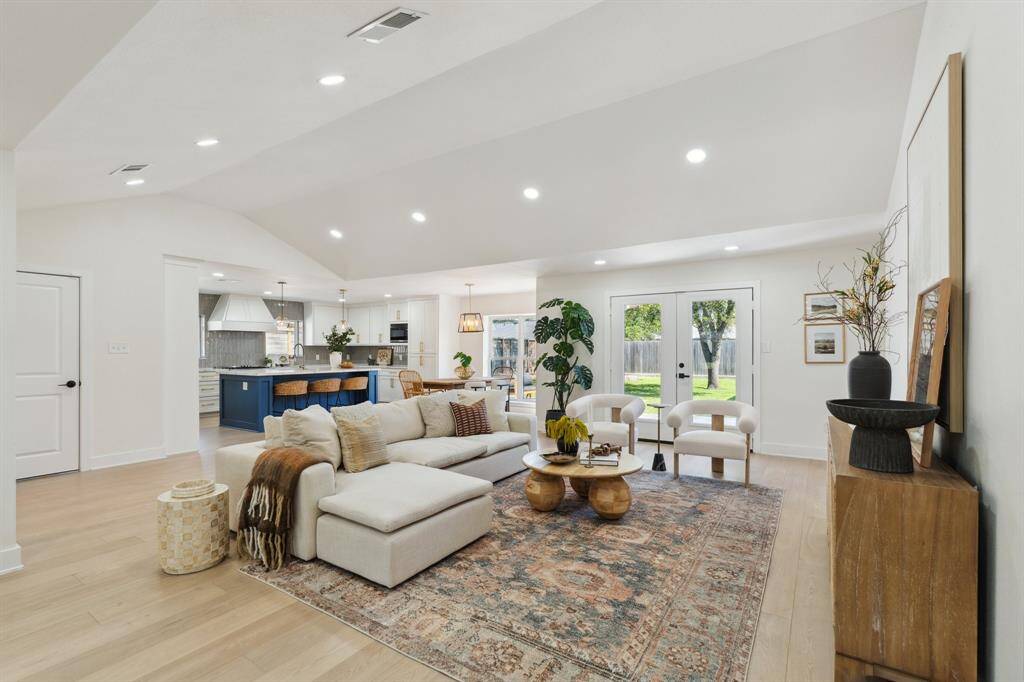 The living room unfolds in a spacious open-concept layout, seamlessly flowing into the adjacent kitchen and dining areas.