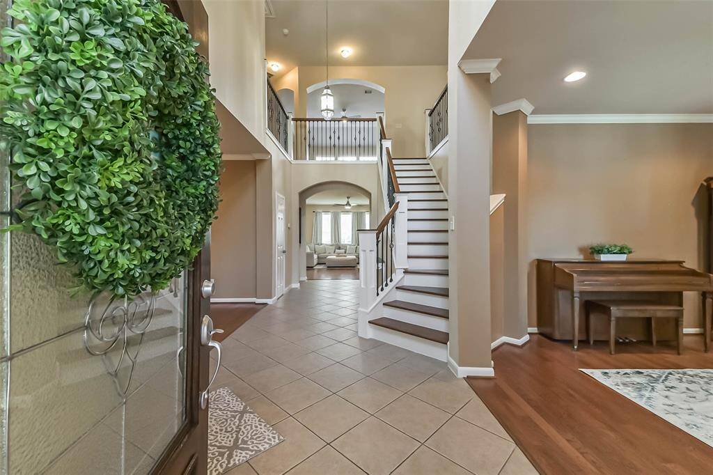 Spacious entryway with a high ceiling, featuring a grand staircase and tile flooring. The area is well-lit and leads you into your home.