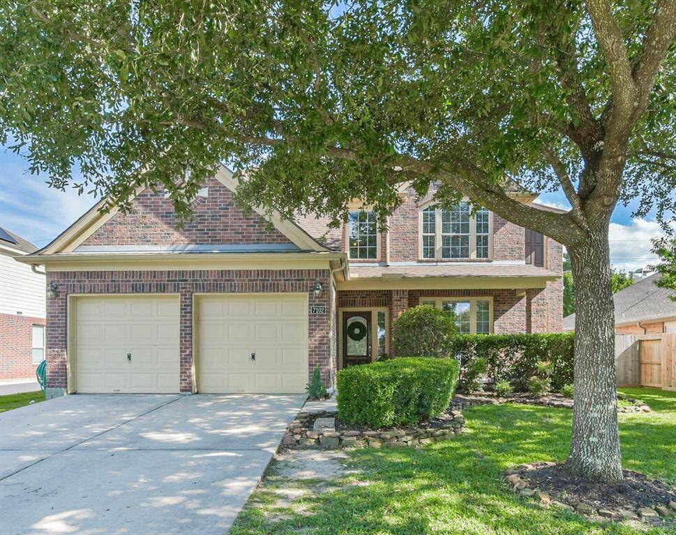 Charming two-story brick home with a double garage, nestled under mature trees. Features a well-maintained front yard and a welcoming entryway and covered front porch.