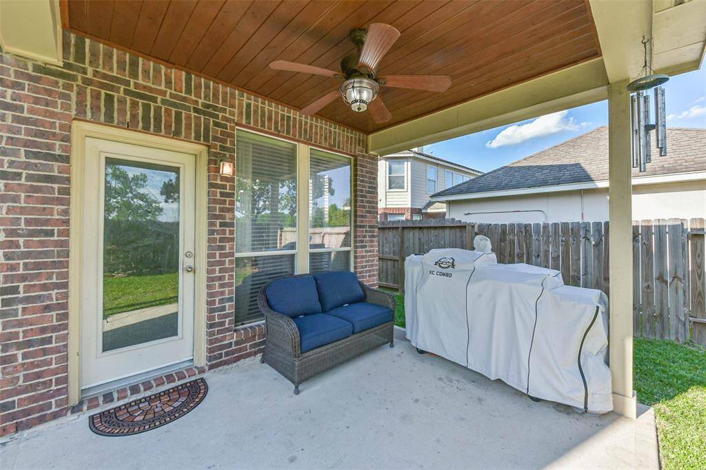 Covered patio with ceiling fan and stained wood shiplap.