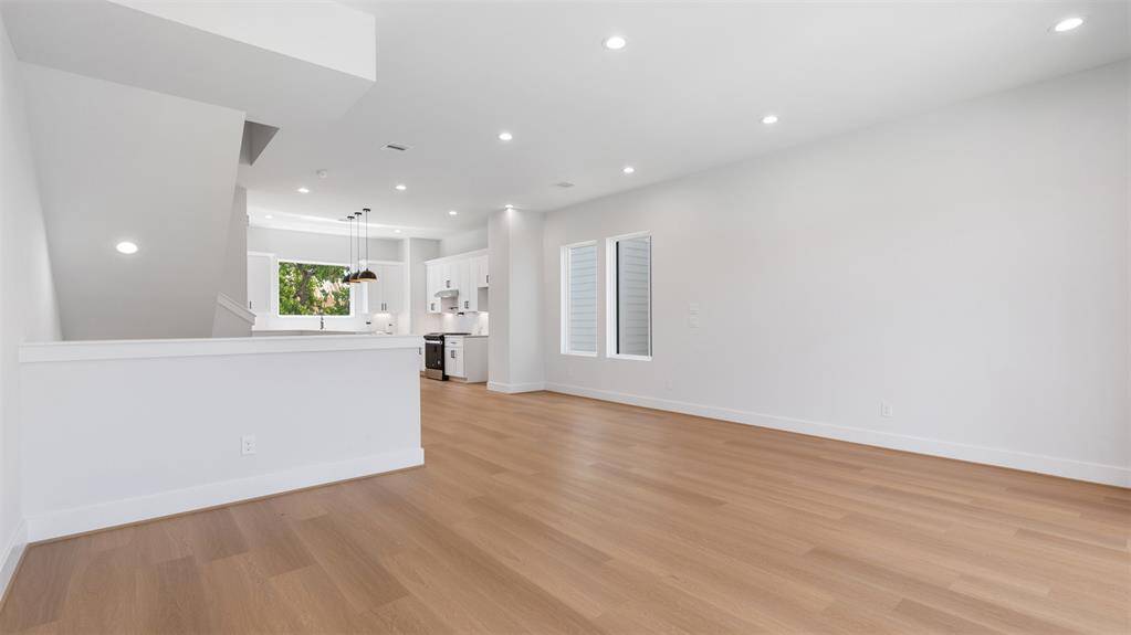 Living room features beautiful flooring, recessed lighting, high ceilings, and large windows.