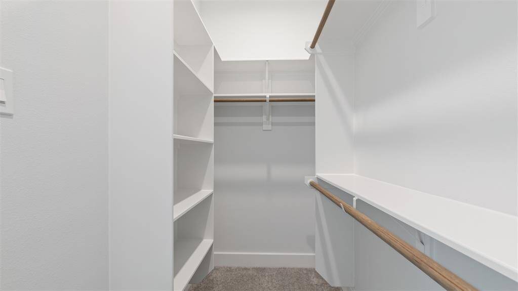 The walk-in closet features plush carpet and plenty of storage space.